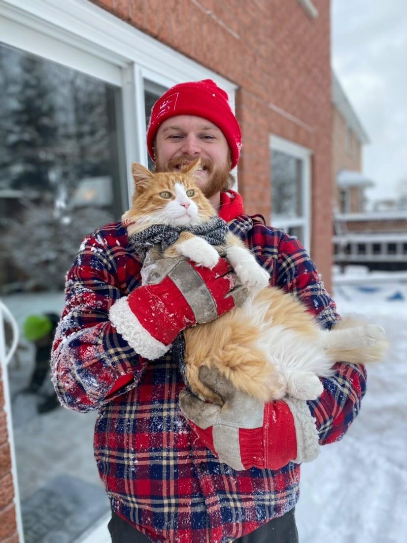 Owen holding a cat while wearing a red hat and gloves